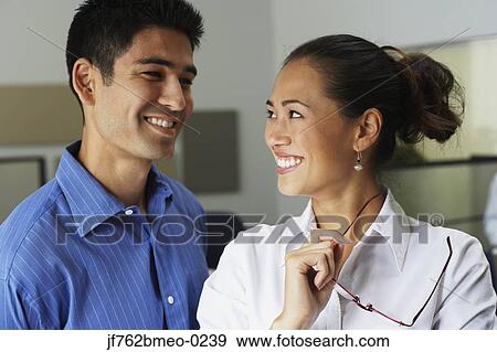 Stock Photo - Asian businesspeople smiling at each other. Fotosearch