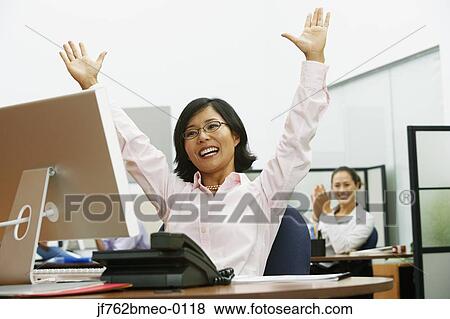 Asian businesswoman cheering at desk View Large Photo Image Stock Photo - Asian businesswoman cheering at desk. Fotosearch