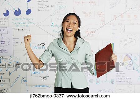 Asian businesswoman cheering in front of whiteboard View Large Photo Image Stock Photo - Asian businesswoman cheering in front of whiteboard. Fotosearch