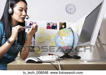Asian businesswoman filing fingernails at desk View Large Photo Image Stock Photo - Asian businesswoman filing fingernails at desk. Fotosearch