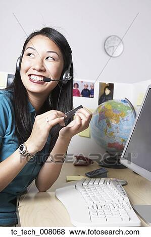 Stock Photo - Asian businesswoman filing fingernails at desk. Fotosearch