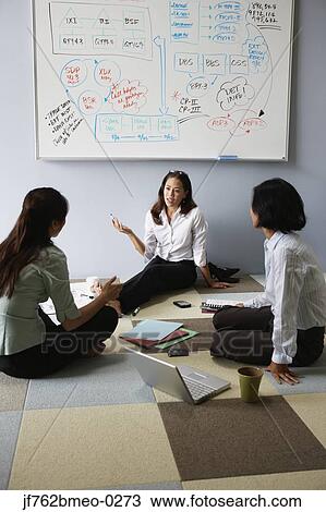 Stock Image - Asian businesswoman having meeting on floor. Fotosearch
