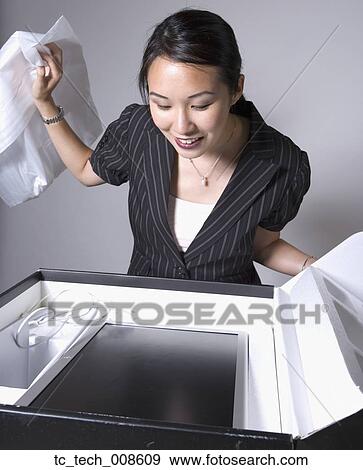 Stock Photo - Asian businesswoman opening box with new computer. Fotosearch