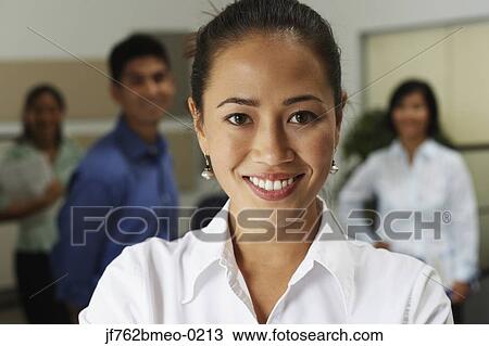 Asian businesswoman smiling with coworkers in background View Large Photo Image Stock Image - Asian businesswoman smiling with coworkers in background. Fotosearch