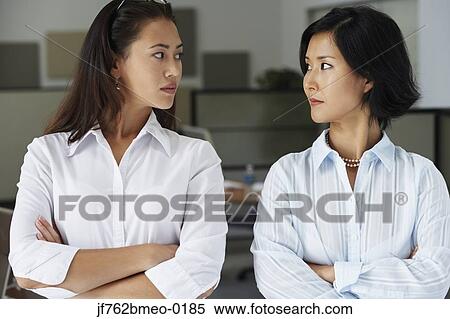 Asian businesswomen looking at each other in office View Large Photo Image Stock Photography - Asian businesswomen looking at each other in office. Fotosearch