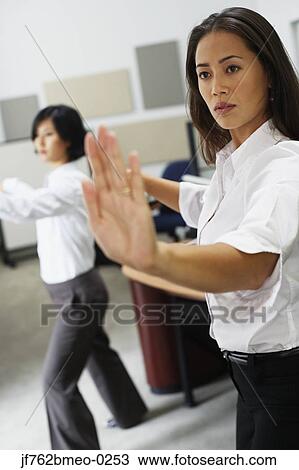 Stock Image - Asian businesswomen practicing tai chi. Fotosearch