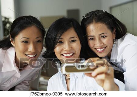 Stock Photography - Asian businesswomen taking own photograph. Fotosearch