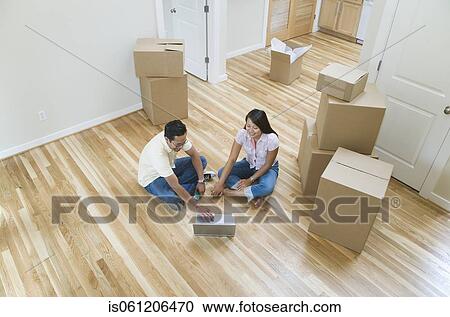 Asian couple looking at laptop in new house View Large Photo Image Stock Image - Asian couple looking at laptop in new house . Fotosearch