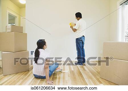 Picture - Asian couple looking at paint swatches in new house. Fotosearch