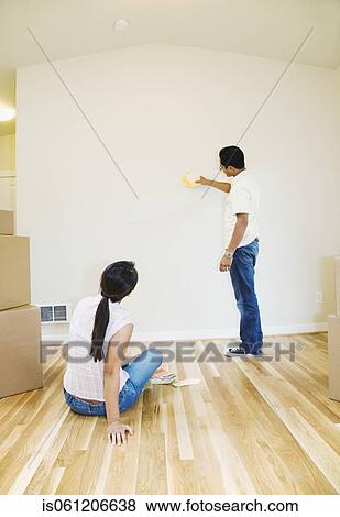 Stock Photo - Asian couple looking at paint swatches in new house. Fotosearch