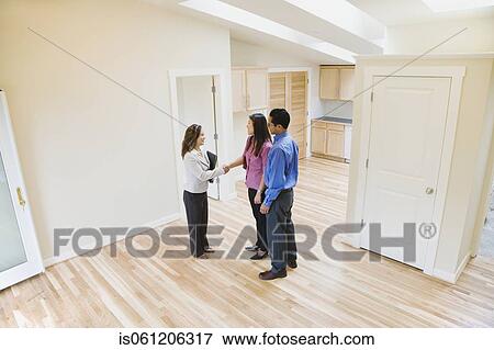 Stock Photo - Asian couple shaking hands with real estate agent in new house. Fotosearch