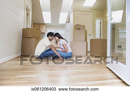 Stock Image - Asian couple smiling at each other in new house . Fotosearch