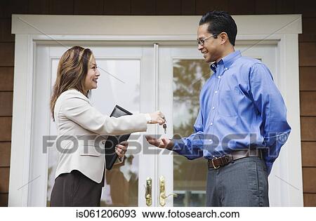 Stock Image - Asian man getting keys from real estate agent. Fotosearch