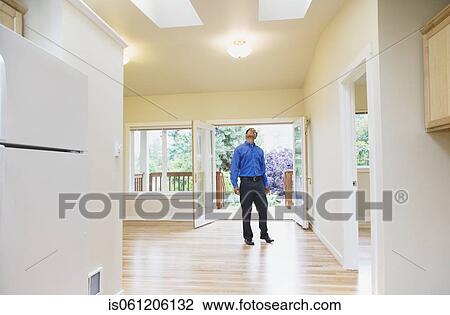 Stock Image - Asian man looking around new house. Fotosearch