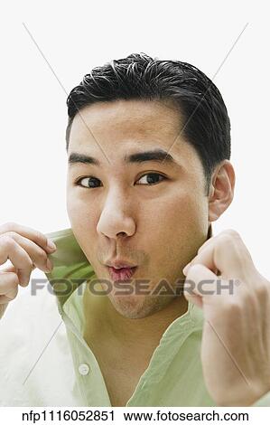 Stock Image - Asian man pulling up shirt collar. Fotosearch
