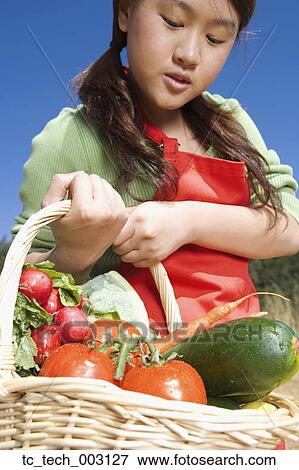 Stock Photo - Asian woman carrying basket of fresh vegetables. Fotosearch