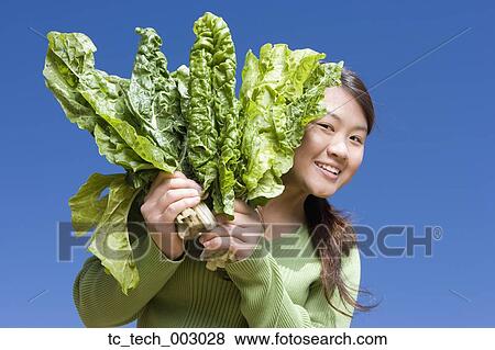 Asian woman holding bunch of green leaf vegetables View Large Photo Image Stock Photo - Asian woman holding bunch of green leaf vegetables. Fotosearch