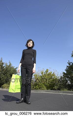 Stock Photograph - Asian woman holding shopping bag outdoors. Fotosearch