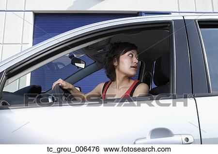 Stock Photograph - Asian woman looking over shoulder in car. Fotosearch