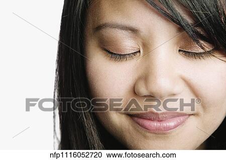 Stock Image - Asian woman smiling with eyes closed. Fotosearch