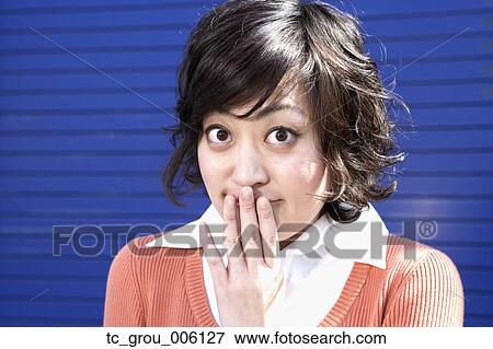 Stock Photo - Close up of Asian woman with hand over mouth. Fotosearch