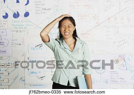 Stock Photography - Frustrated Asian businesswoman in front of whiteboard. Fotosearch