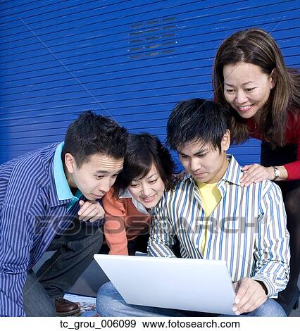 Group of young businesspeople looking at laptop View Large Photo Image Stock Photo - Group of young businesspeople looking at laptop. Fotosearch
