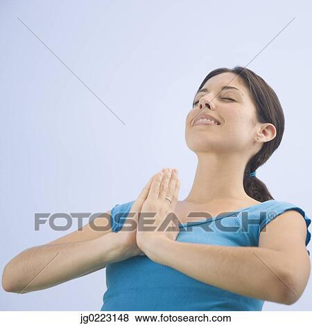 Stock Photo - Low angle view of Hispanic woman praying. Fotosearch