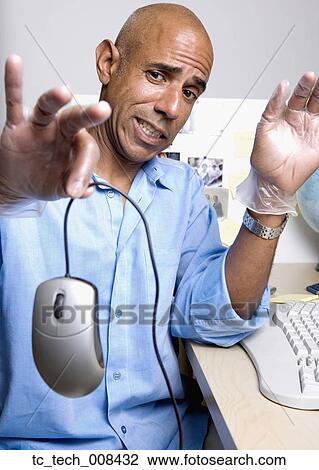 Stock Image - Middle-aged African businessman holding computer mouse. Fotosearch