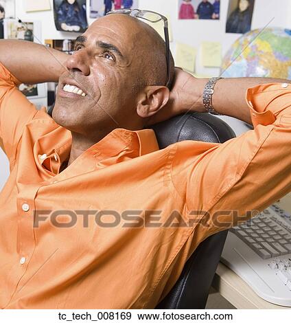 Stock Photo - Middle-aged African businessman with hands behind head. Fotosearch