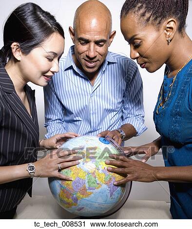 Multi-ethnic businesspeople looking a globe View Large Photo Image Stock Image - Multi-ethnic businesspeople looking a globe. Fotosearch