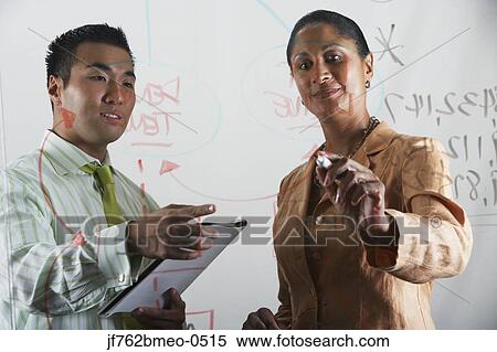 Multi-ethnic businesspeople working on flow chart View Large Photo Image Stock Photography - Multi-ethnic businesspeople working on flow chart. Fotosearch