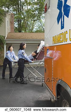Stock Photo - Paramedics putting woman into ambulance. Fotosearch