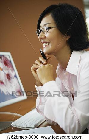 Stock Image - Portrait of Asian businesswoman at desk. Fotosearch