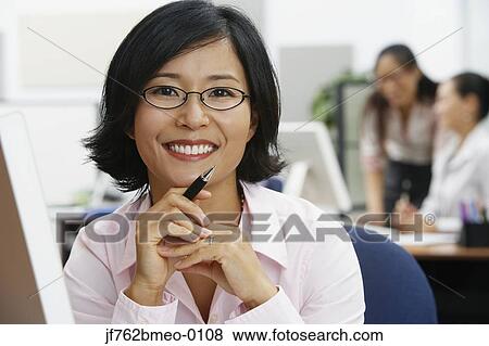 Stock Photo - Portrait of Asian businesswoman holding pen. Fotosearch