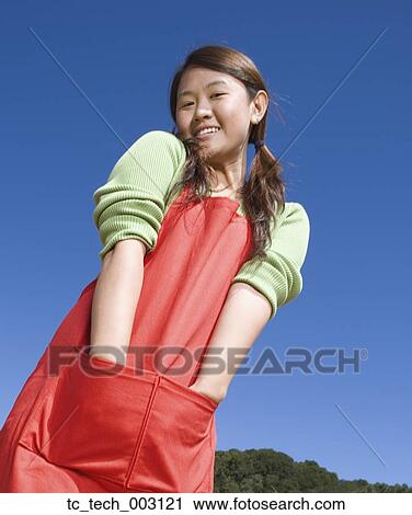 Stock Image - Portrait of Asian woman with hands in apron pockets. Fotosearch
