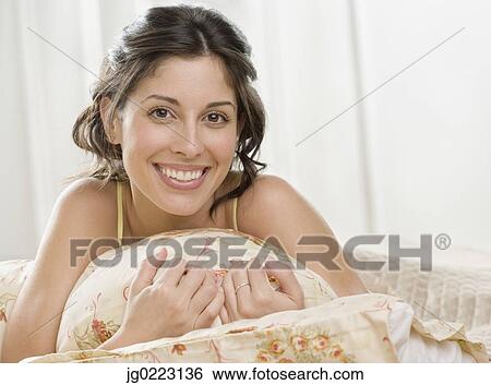 Stock Photograph - Portrait of Hispanic woman laying on bed. Fotosearch