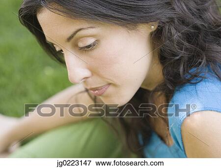 Stock Photo - Portrait of Hispanic woman sitting in grass. Fotosearch