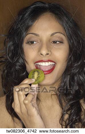 Stock Image - Portrait of Middle Eastern woman eating kiwi slice . Fotosearch