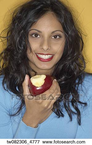 Stock Photo - Portrait of Middle Eastern woman eating apple. Fotosearch