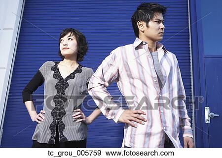 Stock Photo - Portrait of young couple with hands on hips. Fotosearch
