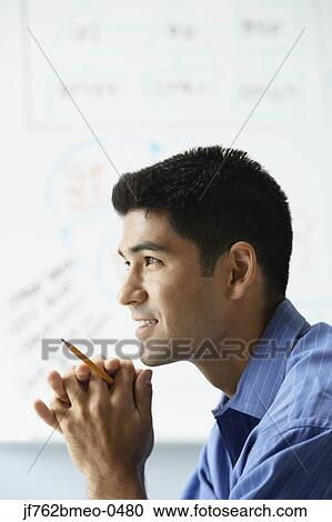 Stock Image - Profile of Asian businessman in front of whiteboard. Fotosearch