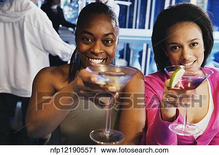 Stock Image - Two African women toasting with cocktails. Fotosearch