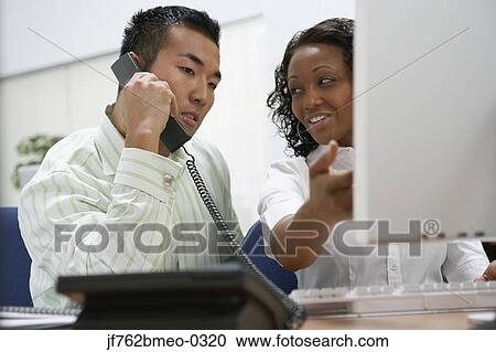 Stock Image - Two businesspeople working at desk. Fotosearch