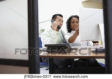 Stock Photo - Two businesspeople working at desk. Fotosearch