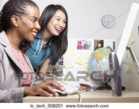 Stock Image - Two businesswomen looking at computer. Fotosearch