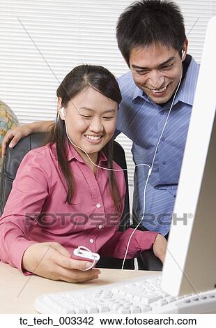 Two young businesspeople listening to mp3 player View Large Photo Image Stock Image - Two young businesspeople listening to mp3 player. Fotosearch