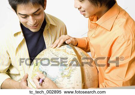 Two young men looking at globe View Large Photo Image Stock Photography - Two young men looking at globe . Fotosearch