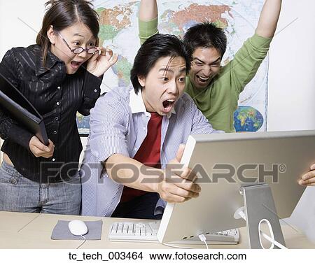 Young businesspeople cheering and looking at computer View Large Photo Image Picture - Young businesspeople cheering and looking at computer. Fotosearch