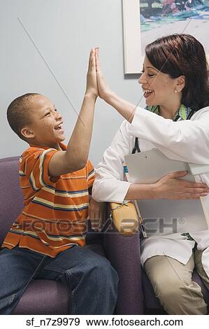 African boy and Hispanic female doctor high-fiving in waiting room View Large Photo Image Stock Photo - African boy and Hispanic female doctor high-fiving in waiting room. Fotosearch
